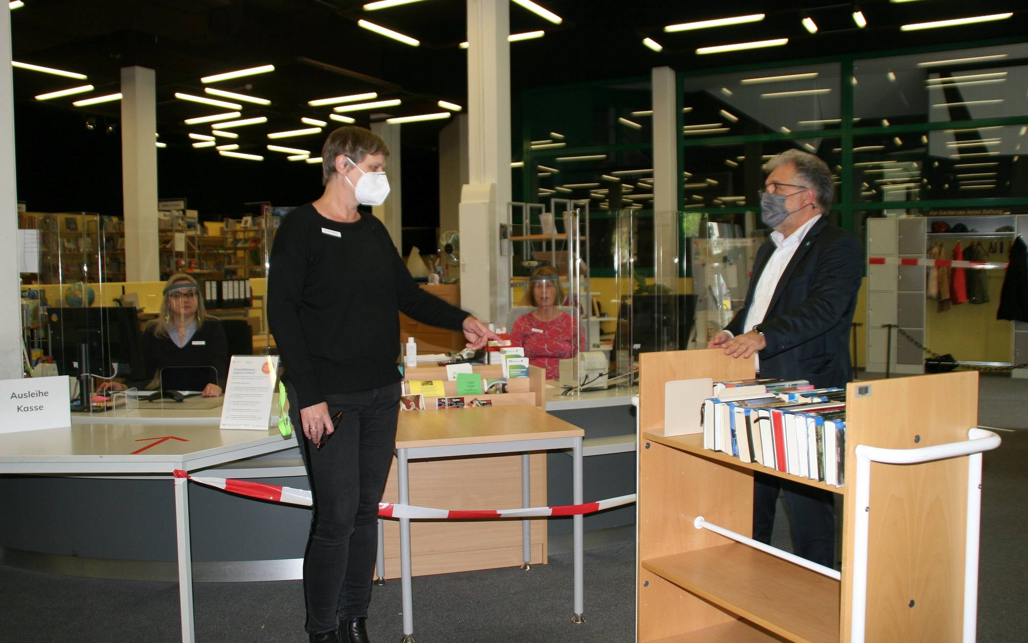  Bürgermeister Thomas Dinkelmann im Gespräch mit Bibliotheksleiterin Ursula Leifeld. Im Hintergrund bereiten sich die Mitarbeiterinnen Iryna Ostapenko (l.) und Petra Kampf auf den ersten Ansturm auf die Bibliothek. vor. 