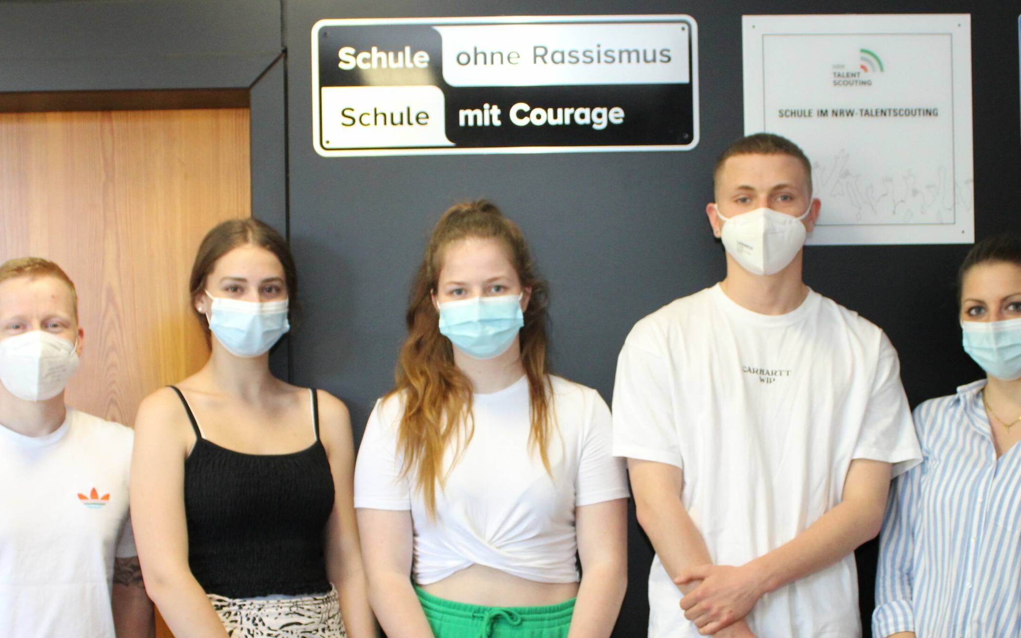  Lehrer Thomas Krei, Schülerinnen Amelie Karsten und Tina Kranz, Schüler Carlo Ebeling und Lehrerin Vassiliki Zachari posieren unter dem Schild, das die Schule als Teil des Netzwerks „Schule ohne Rassimus“ ausweist.. 