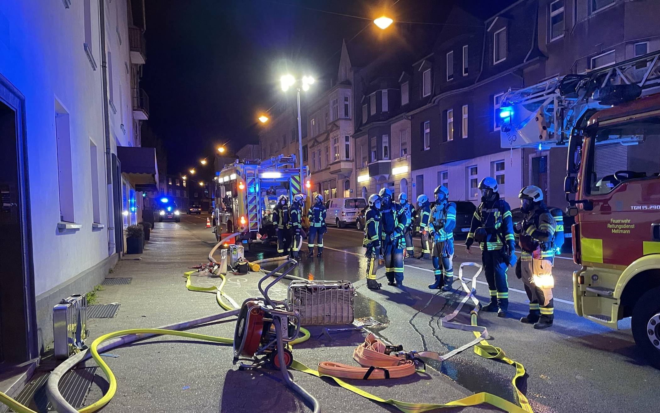  Zimmerbrand in Mehrfamilienhaus - Einsatzkräfte der Feuerwehr Mettmann vor dem Hauseingang. 