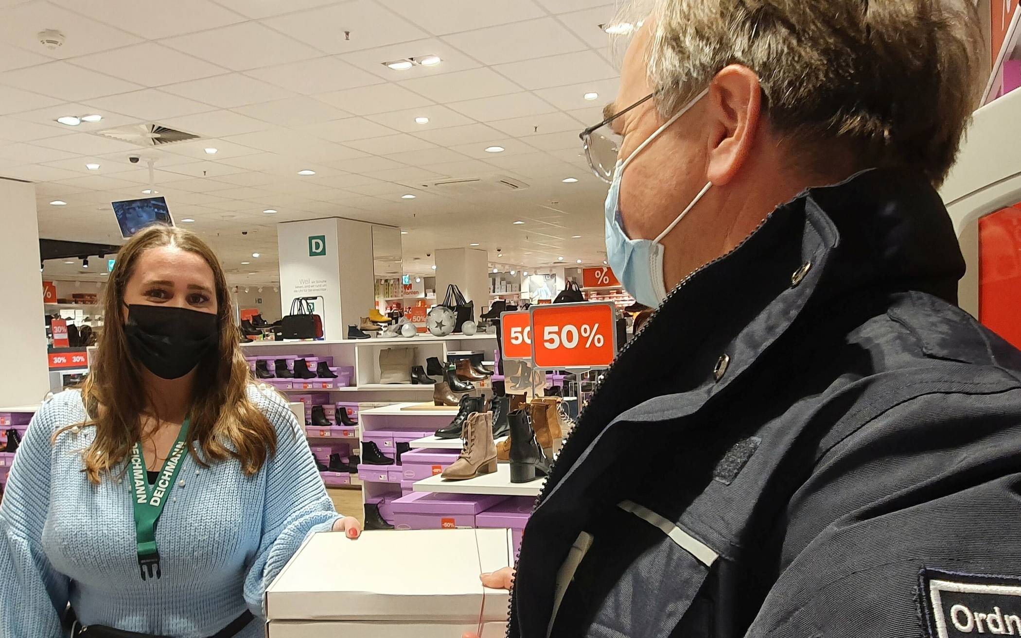  Ein Mitarbeiter der Ordnungsbehörde überreicht die 2G-Bändchen in einem Schuhgeschäft. 