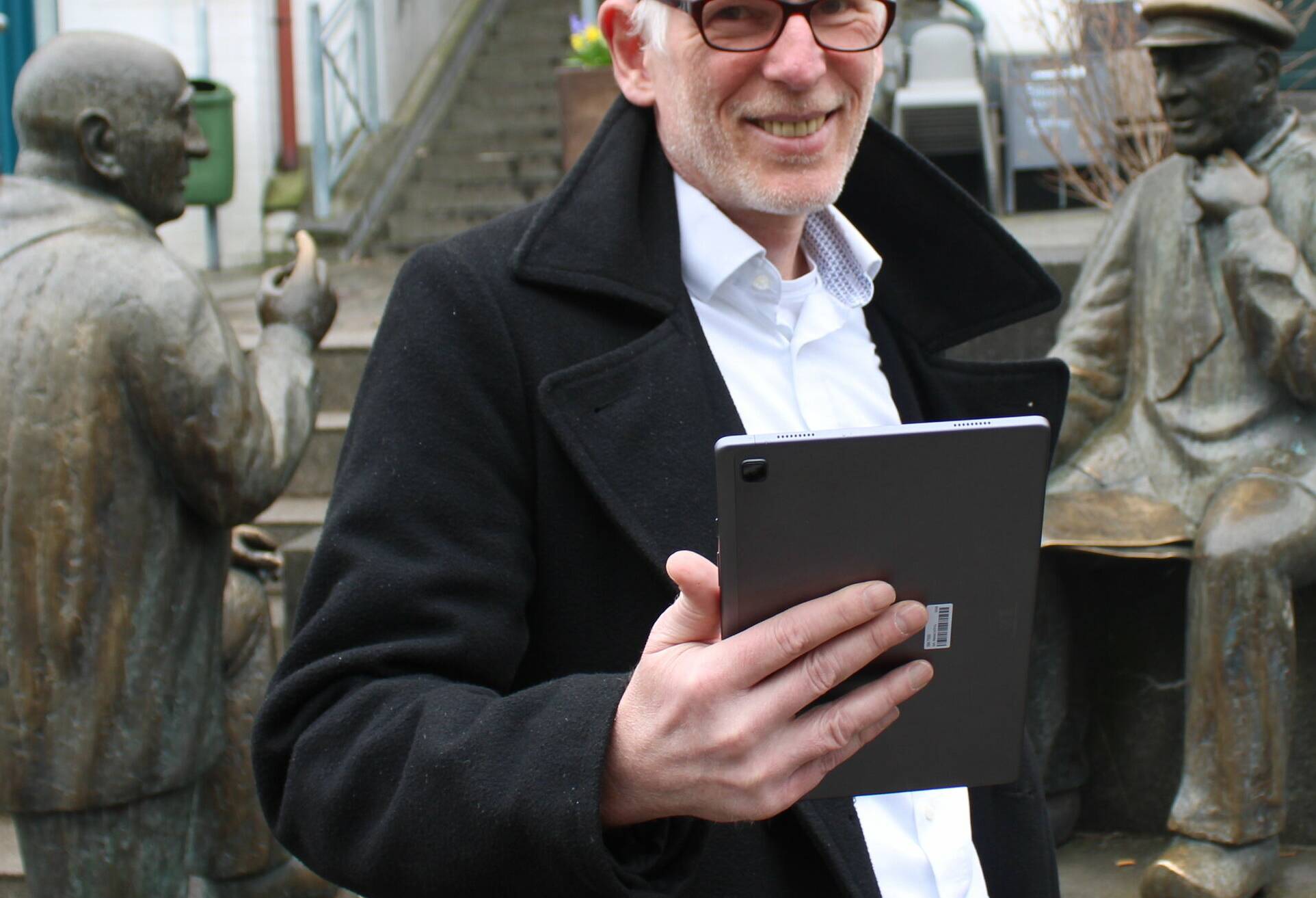  Bernd Wychlacz mit Tablet vor einer der Stationen seiner Stadtführungs-App: den parlierenden Herren an der Mühlenstraße. 