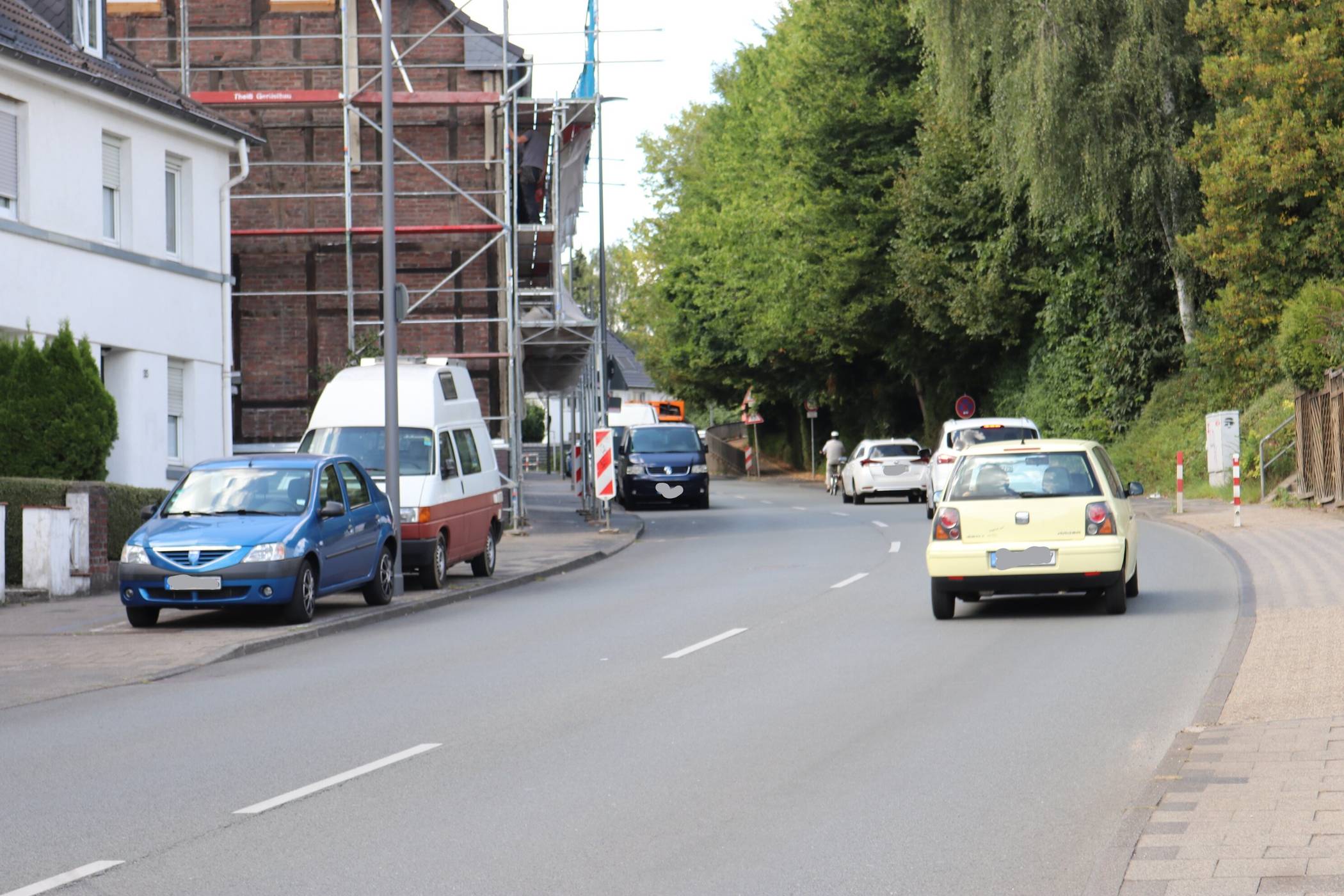  Brenzlige Situation: Ein Radfahrer fährt vor den Autos die Nordstraße hinauf. Ein Überholmanöver wäre riskant. Oben wartet in Gegenrichtung ein Müllwagen hinter parkenden Autos am Straßenrand, bis die Straße frei ist, damit er an den Fahrzeugen vorbeifahren kann. 
  