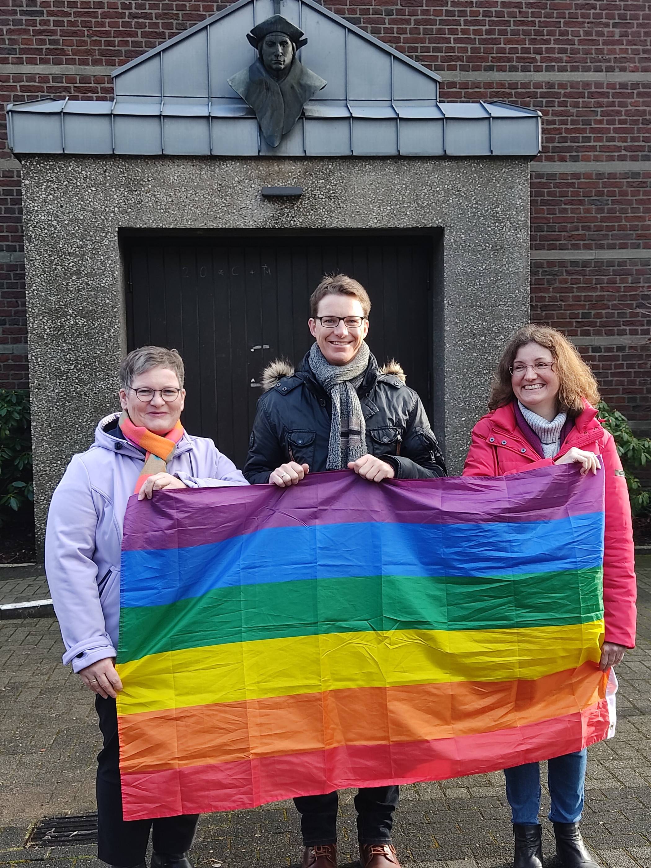 Andrea Lauer, Maximilian Bröhl und Petra Hermes-Wigge mit der Regenbogenflagge. 