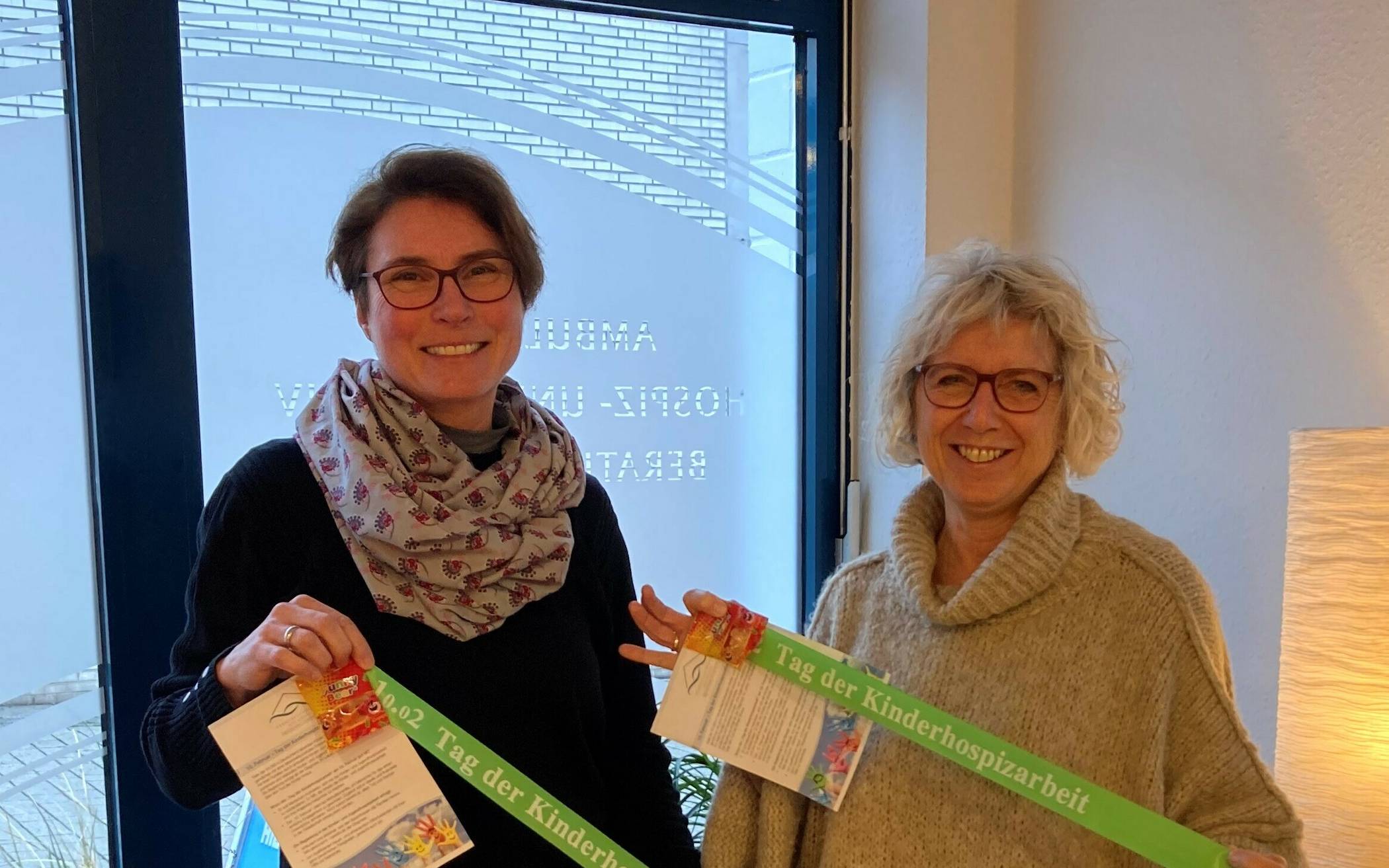  Anke Kaufmann (links) und Kornelia Smailes mit den grünen Bänder und den Flyern, die anlässlich des Tages der Kinderhospizarbeit in Mettmann verteilt werden. 