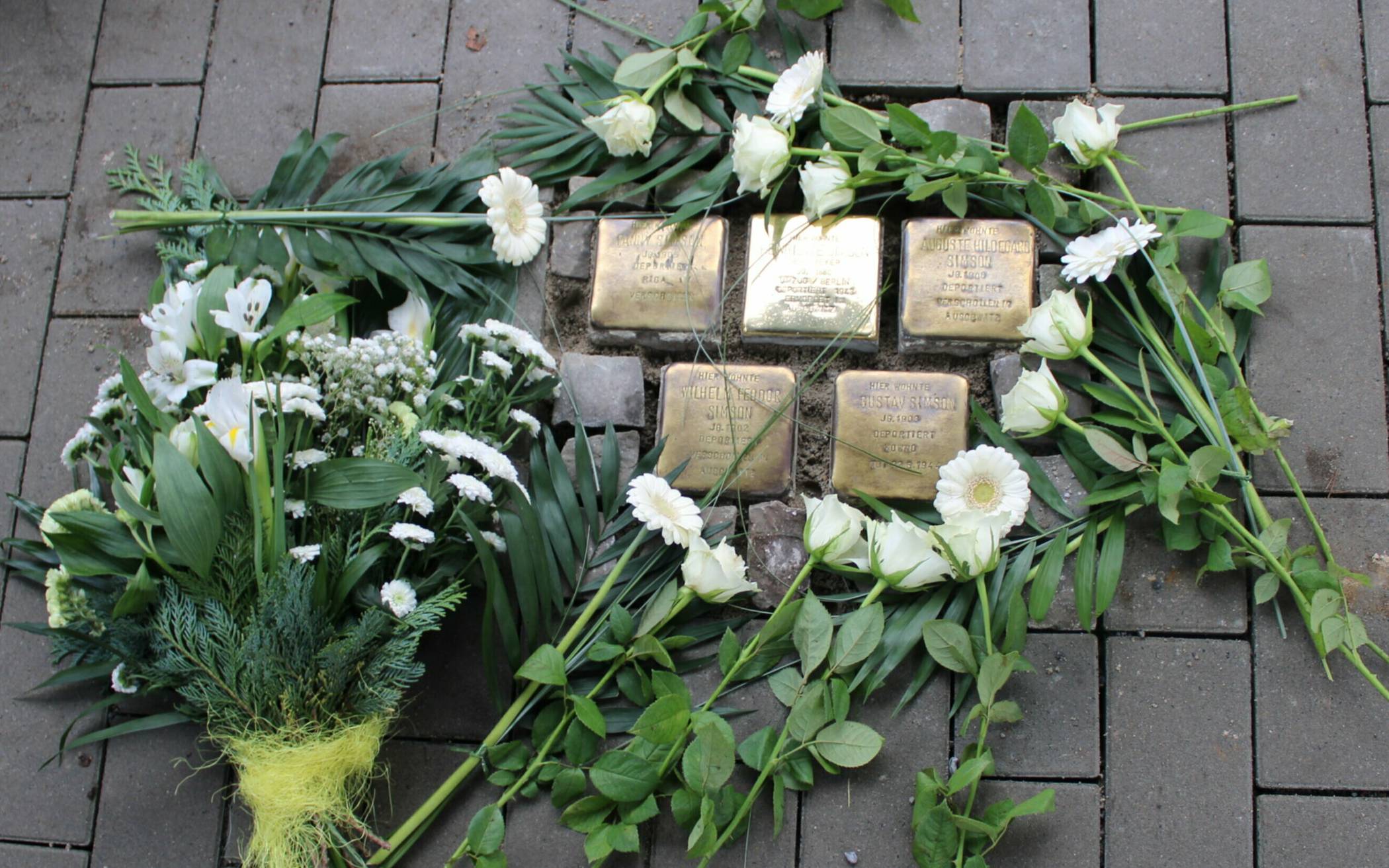 Kinder legten weiße Gerbera an den frisch verlegten Stolpersteinen nieder. 