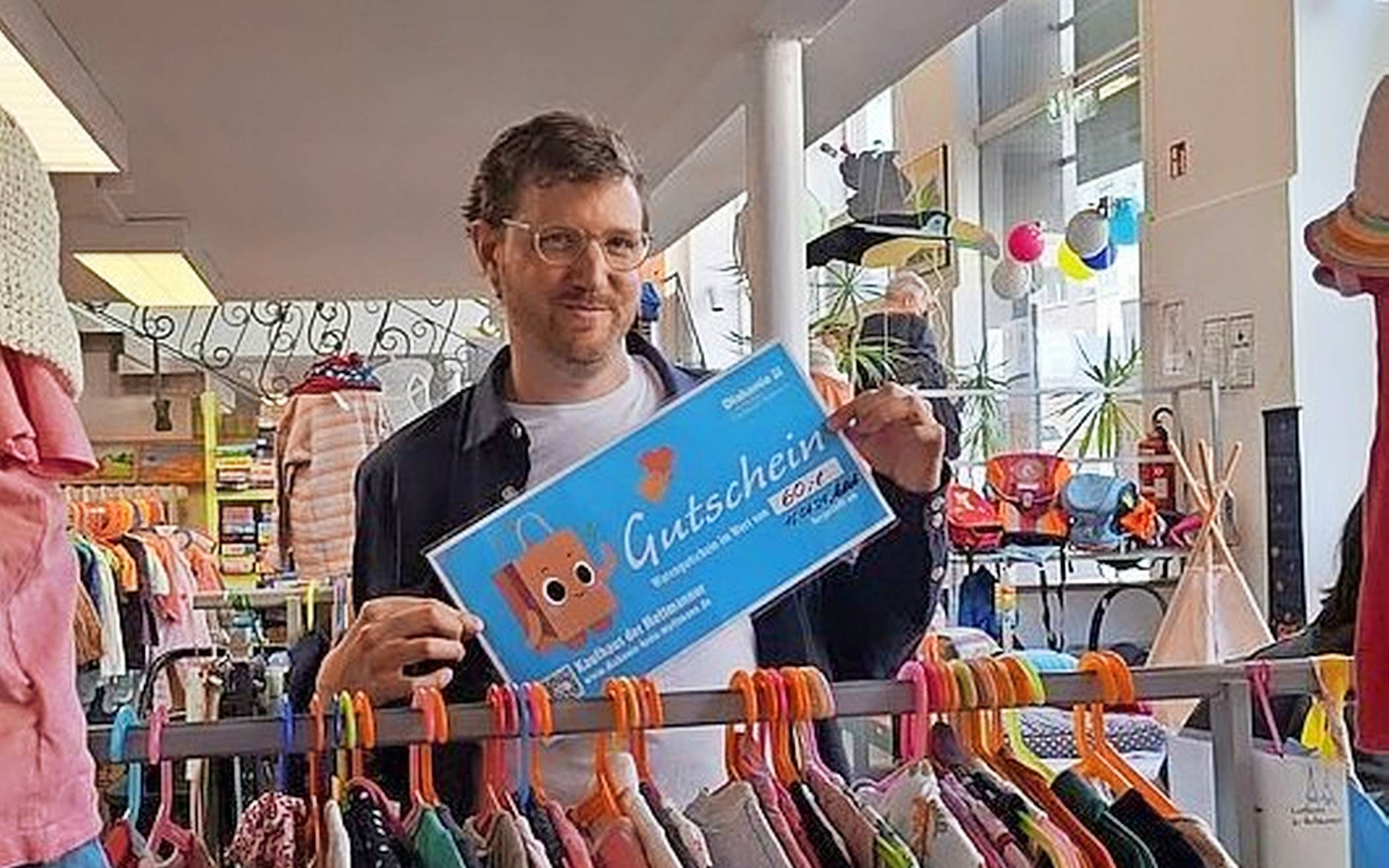Moritz Klees präsentiert einen Gutschein mit Maskottchen Lumi.   