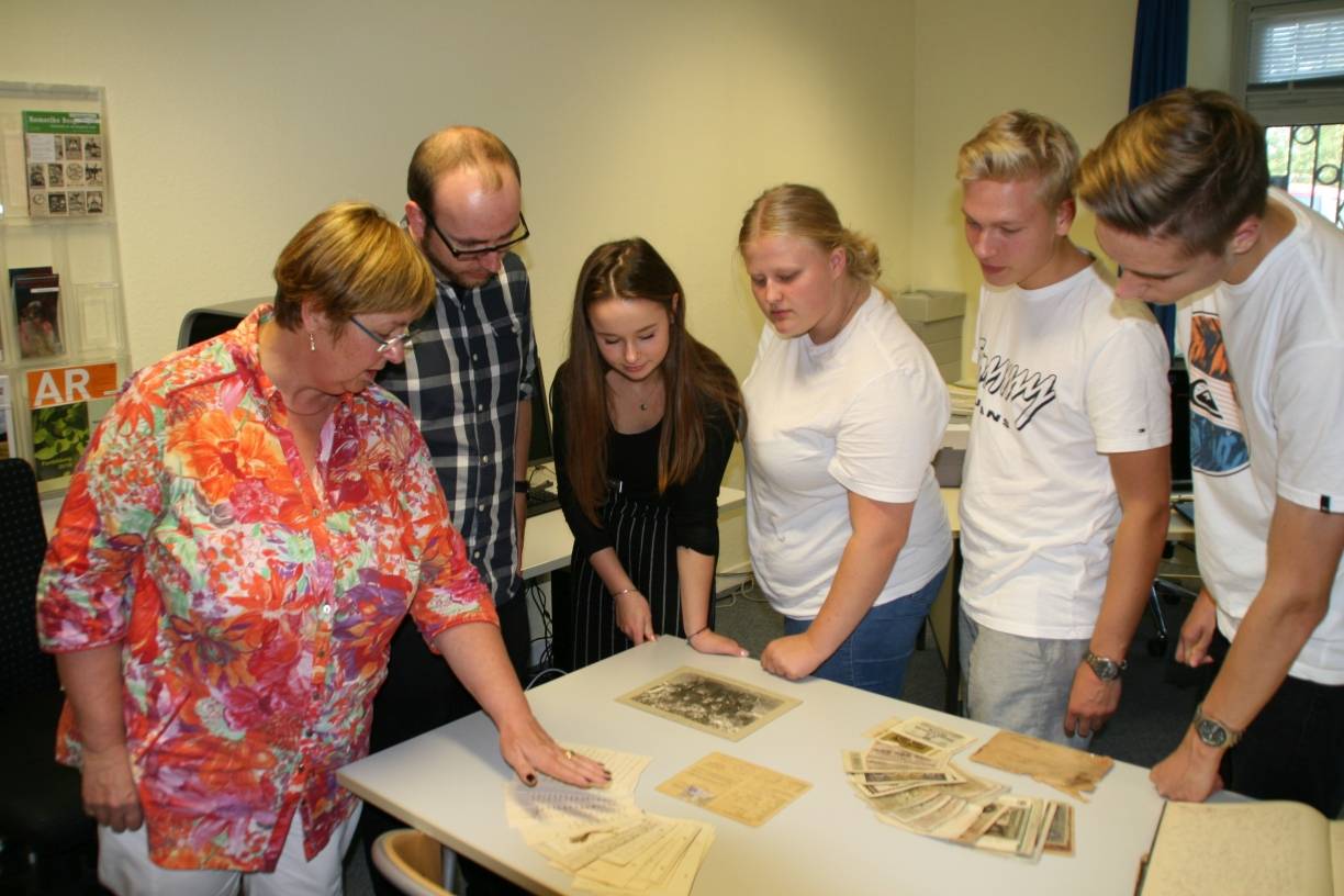  Stadtarchivarin Marie-Luise Carl zeigt Lehrer Carsten Heth und einigen Schülern Feldpostkarten aus dem Ersten Weltkrieg.  