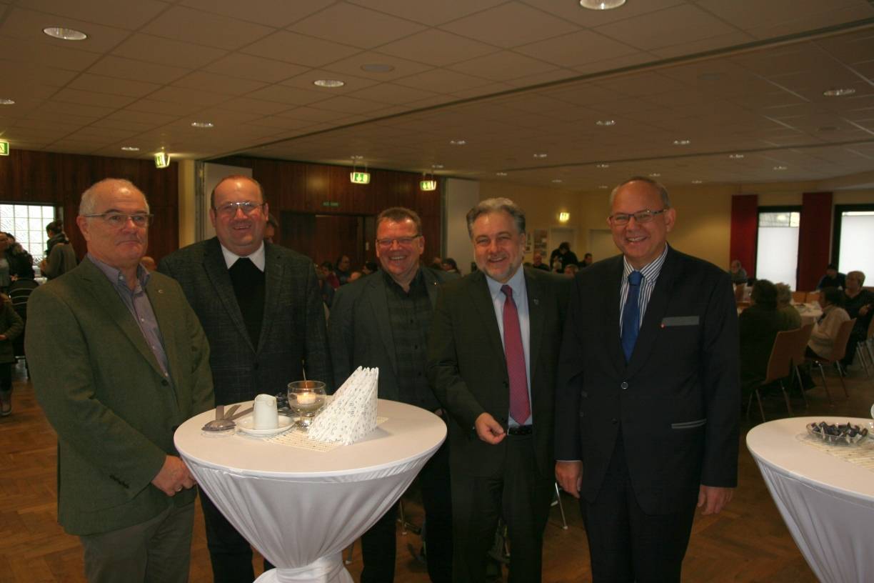  Wilfried Meiswinkel, Vorsitzender der Mettmanner Kolpingsfamilie, Pfarrer Herbert Ullmann, Caritas-Bereichsleiter Thomas Rasch, Bürgermeister Thomas Dinkelmann, und Klaus Gärtner, der Fachdienstleiter der Wohnungslosenhilfe, im vollbesetzten Saal des Kaplan-Flintop-Hauses. 