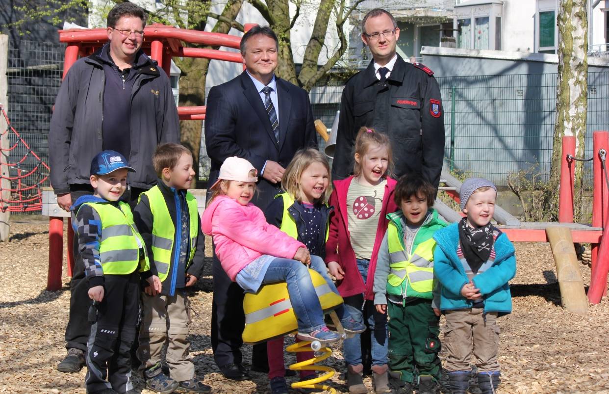 Ferdinand Ortmann (Sachgebietsleiter Grünflächen in der Stadtverwaltung Mettmann), Thomas Döring (Filialleiter der Kreissparkasse in Mettmann) und Benedikt Lamerz (Mitglied der Feuerwehr Mettmann und des Feuerwehr-Fördervereins) mit den Kindern vom Kinderhaus Mettmann. 