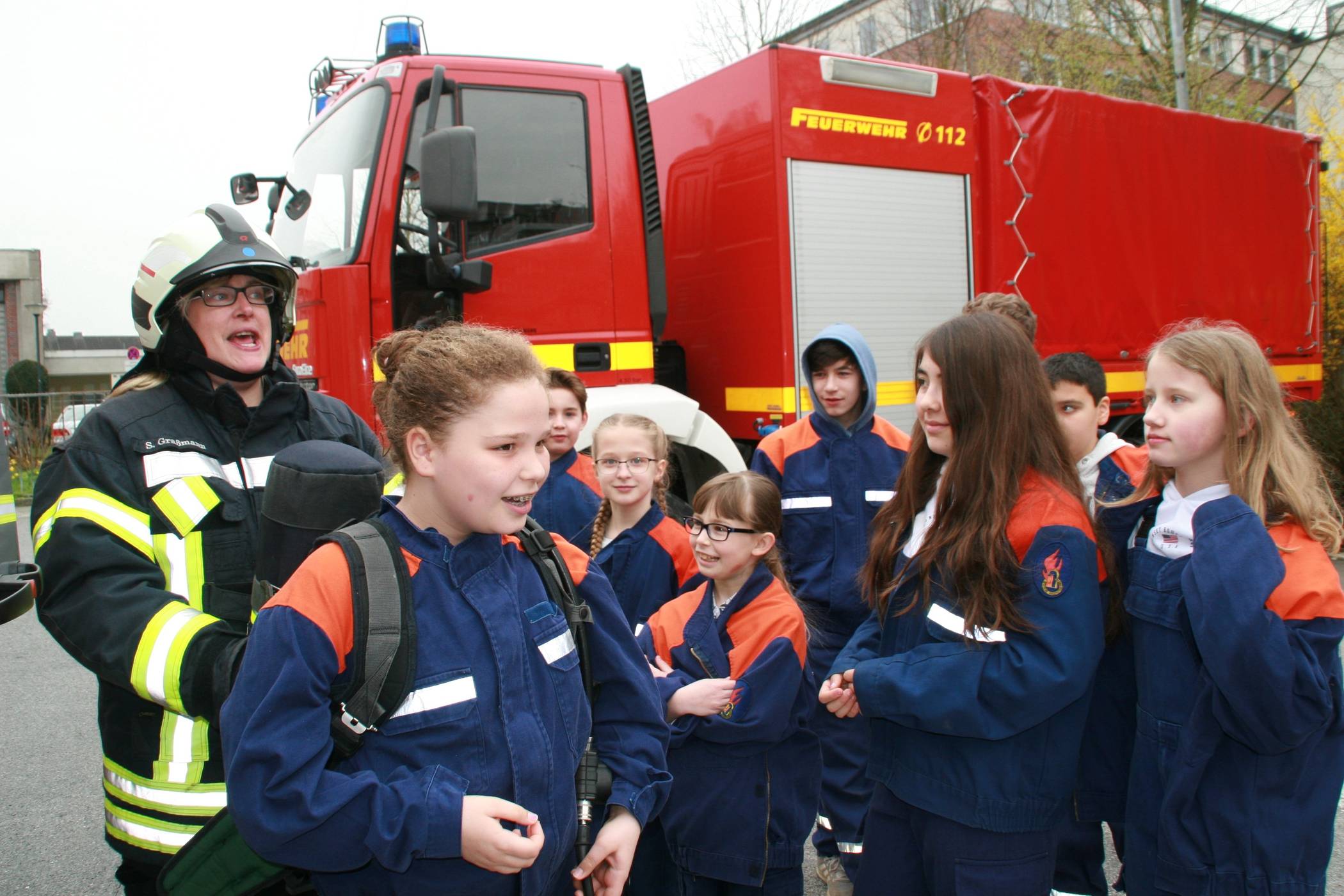  Hauptbrandmeisterin Sandra Graßmann zeigt den Kindern, wie schwer ein Atemschutzgerät ist, das Feuerwehrleute im Ernstfall tragen. Foto: Kreisstadt Mettmann. 