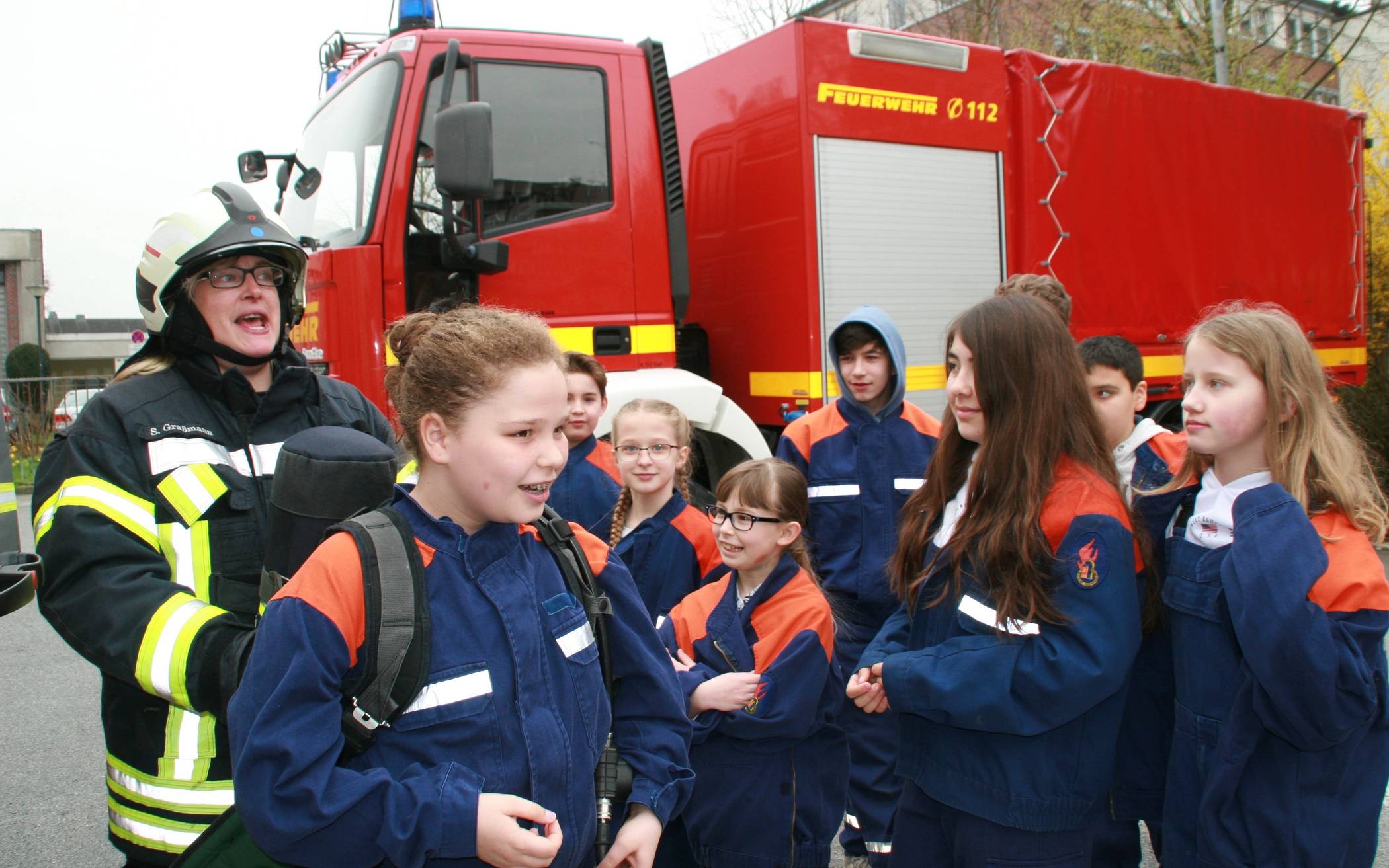  Hauptbrandmeisterin Sandra Graßmann zeigt den Kindern, wie schwer ein Atemschutzgerät ist, das Feuerwehrleute im Ernstfall tragen. Foto: Kreisstadt Mettmann. 