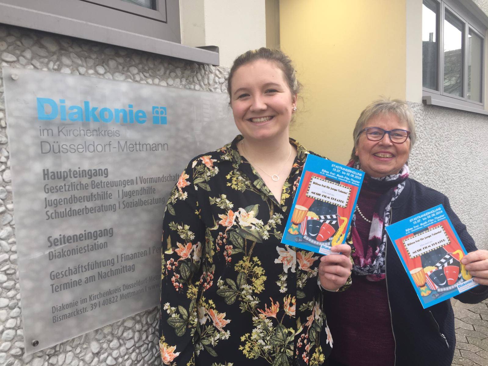  Lea Pulst (l.) und Renate Voortman präsentieren den Anmeldeflyer, der ab sofort in allen Mettmanner Schulen, in der Diakonie und  in unterschiedlichen Institutionen ausliegt. 