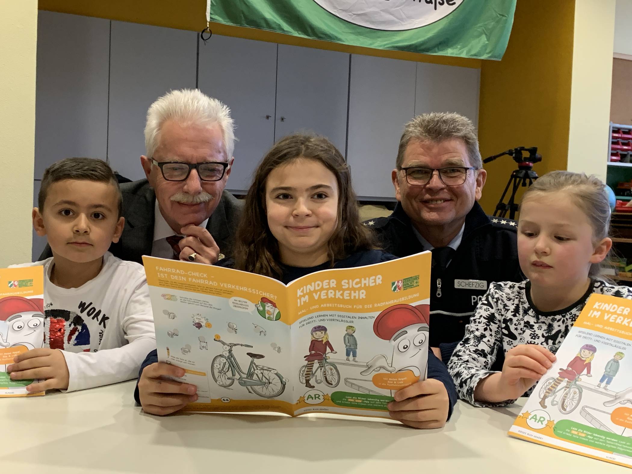  Landrat Thomas Hendele und Ralf Schefzig, Vorsitzender der Kreisverkehrswacht, schauen sich gemeinsam. mit Luca, Emily und Ronja (v.l), Schülersprecher der Grundschule Kuhstraße in Velbert, die neuen Arbeitshefte an.   