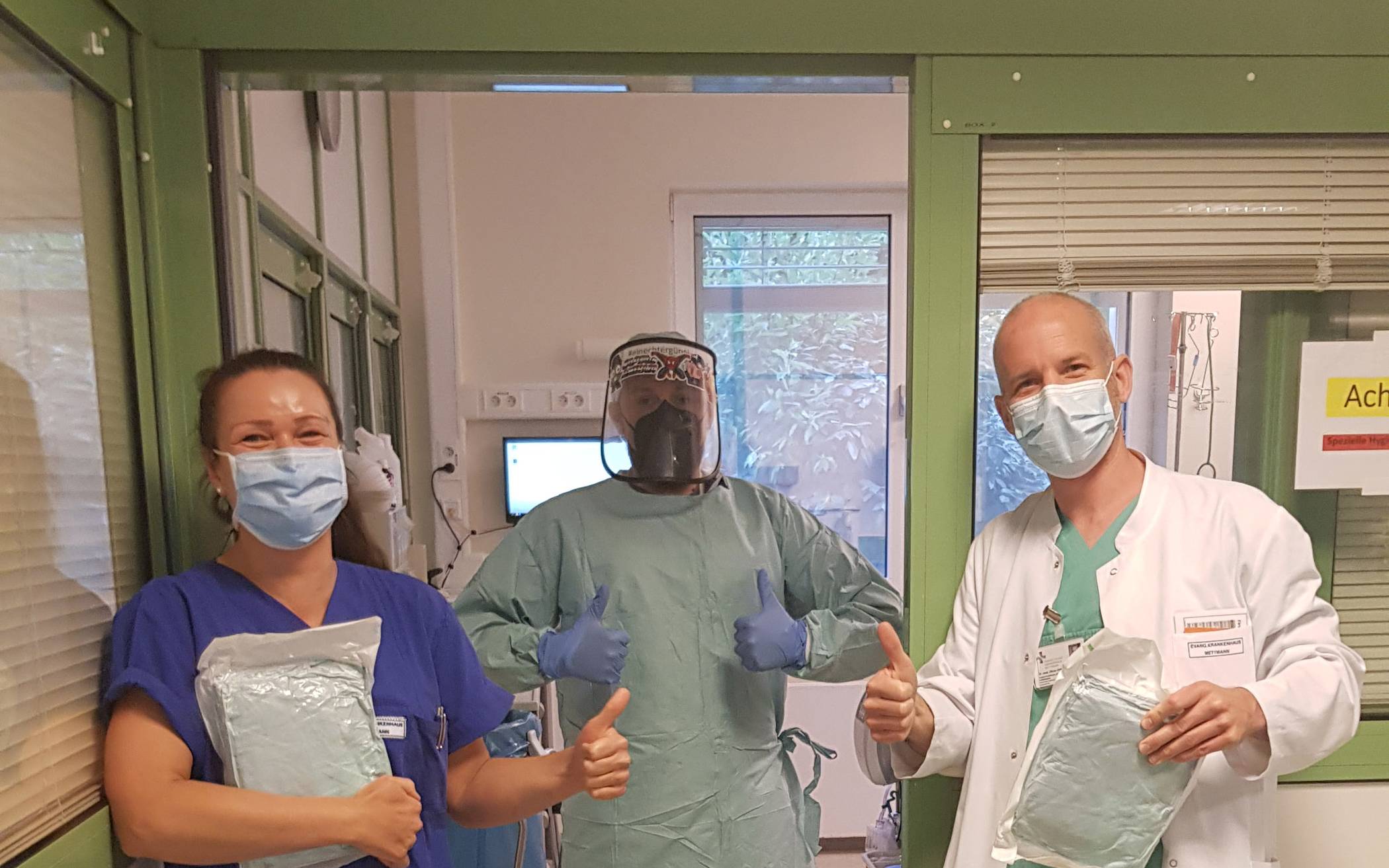  Der Chefarzt der Anästhesie, Intensiv- und Notfallmedizin, Dr. med. Oliver Hofer freut sich mit zwei Intensiv-Pflegkräften über Schutzkittel. 