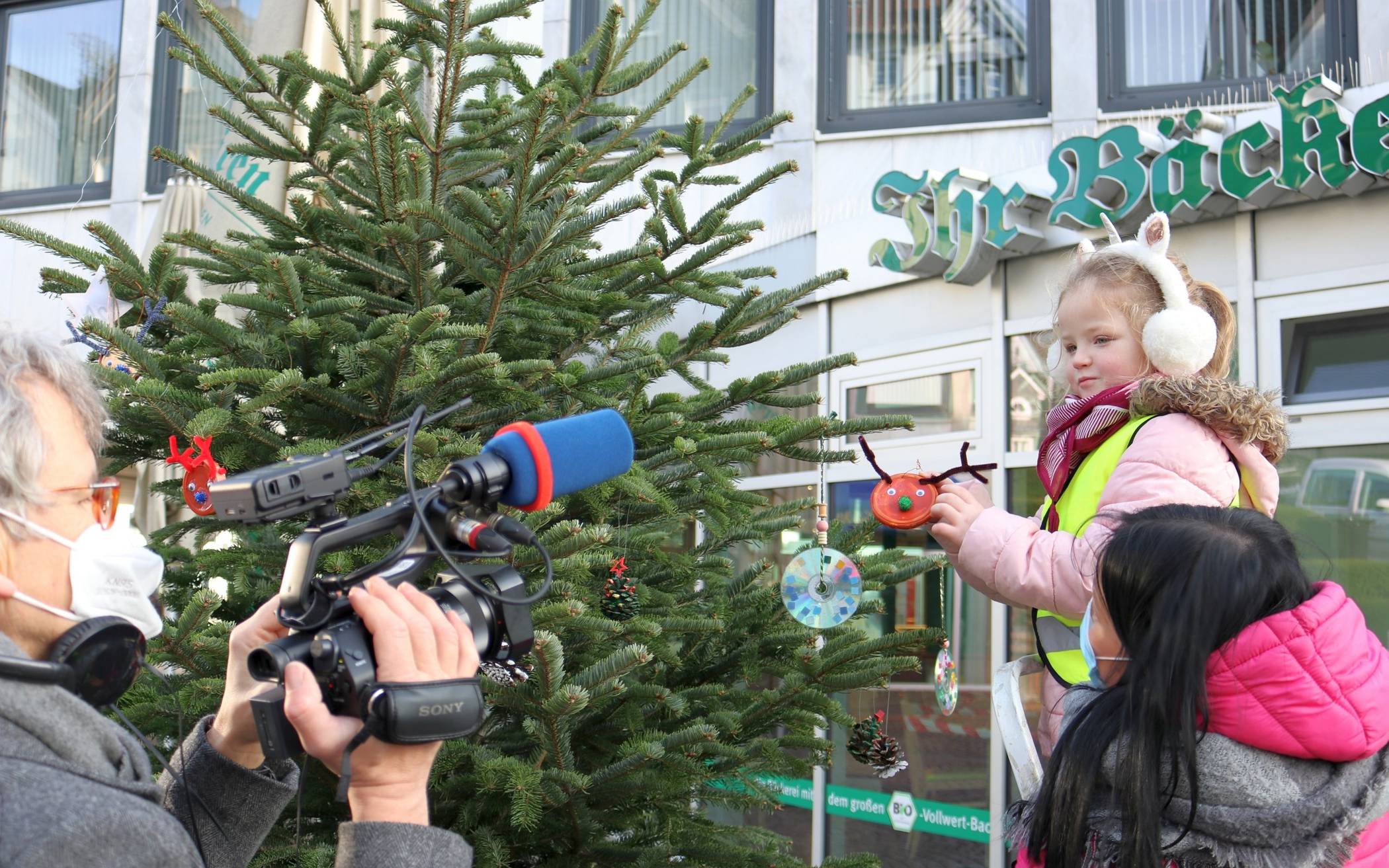 Kinder schmücken Baum vor laufender Kamera