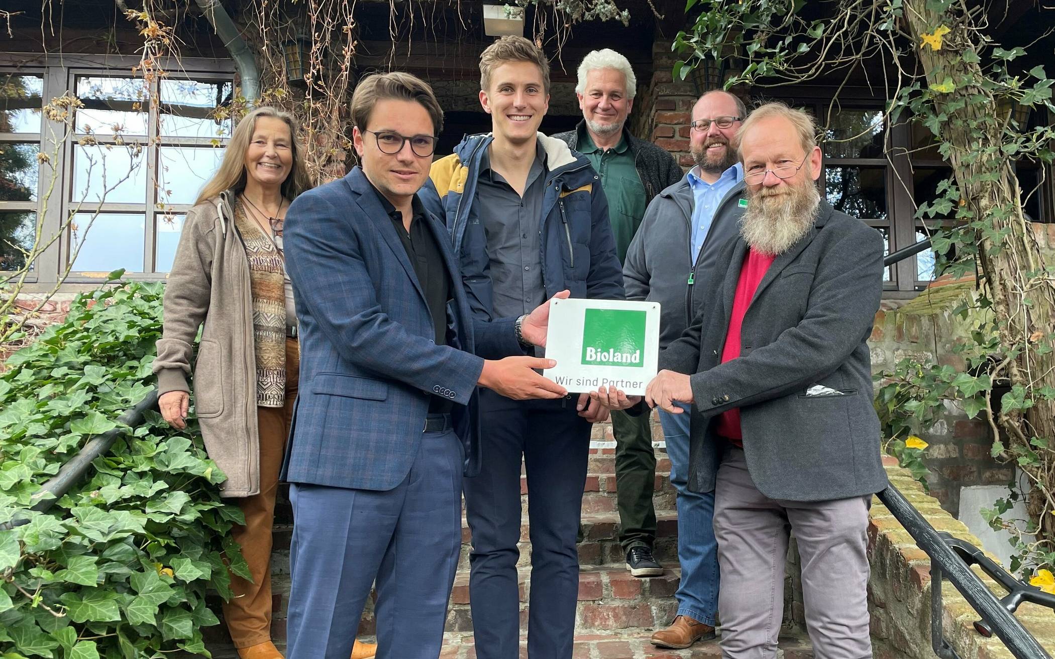  Familie Reucher vom Land Gut Höhne wird das „Wir sind Partner von Bioland“ Schild überreicht: Vorne links Marc-Tilo Reucher, Mitte Kai-Timon Reucher, ganz links Beate Sieben-Reucher und hinten oben Dirk Reucher, Mitte rechts Jan Leifert, vorne rechts Joachim Koop. 